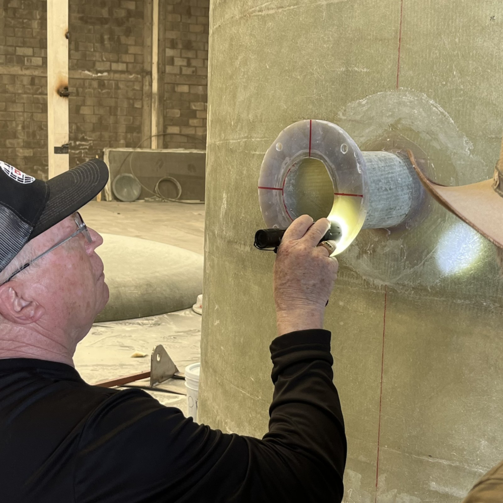 Crimar inspector checking an FRP nozzle and its laminate with a flashlight