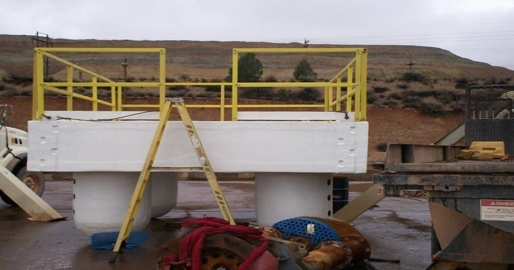 Completed FRP pump barge with yellow handrail and ballast columns standing on site before launch