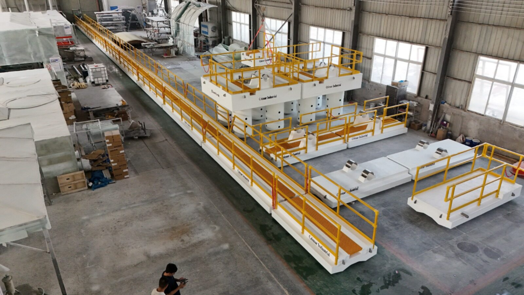 Two FRP pump barges with yellow handrail, floating walkway sections and pipe floats pinned together for fit-up in the fabrication shop