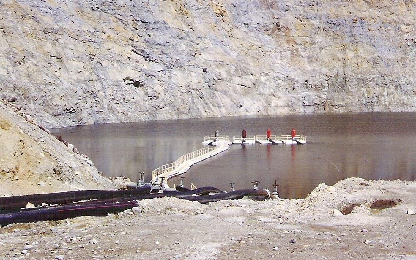 Four FRP pump barges with vertical pumps and a floating fiberglass walkway in service on a mine pit lake