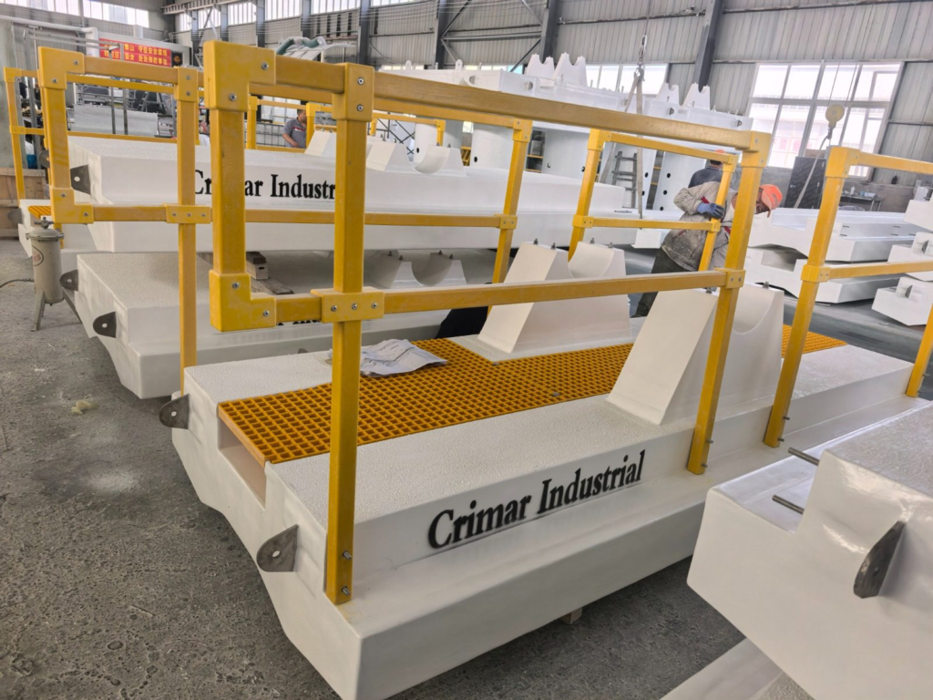 FRP walkway floats with yellow fiberglass handrail, molded grating deck and pipe saddles in the fabrication shop